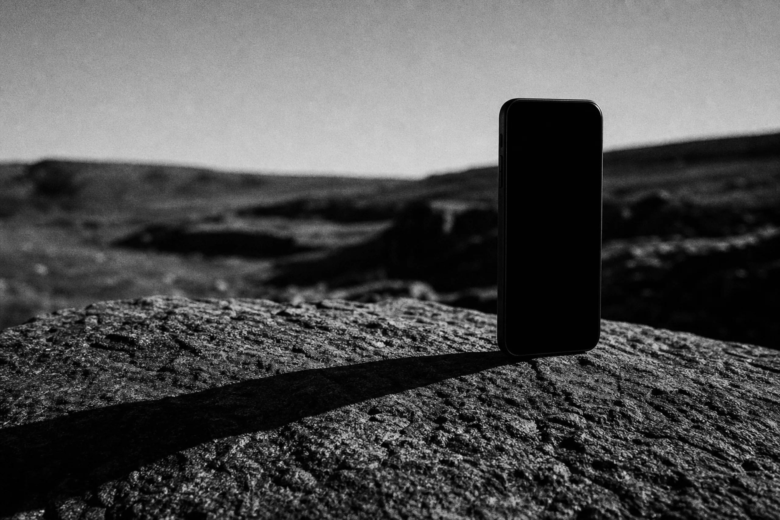 A phone standing upright on cracked rock against a bleak horizon