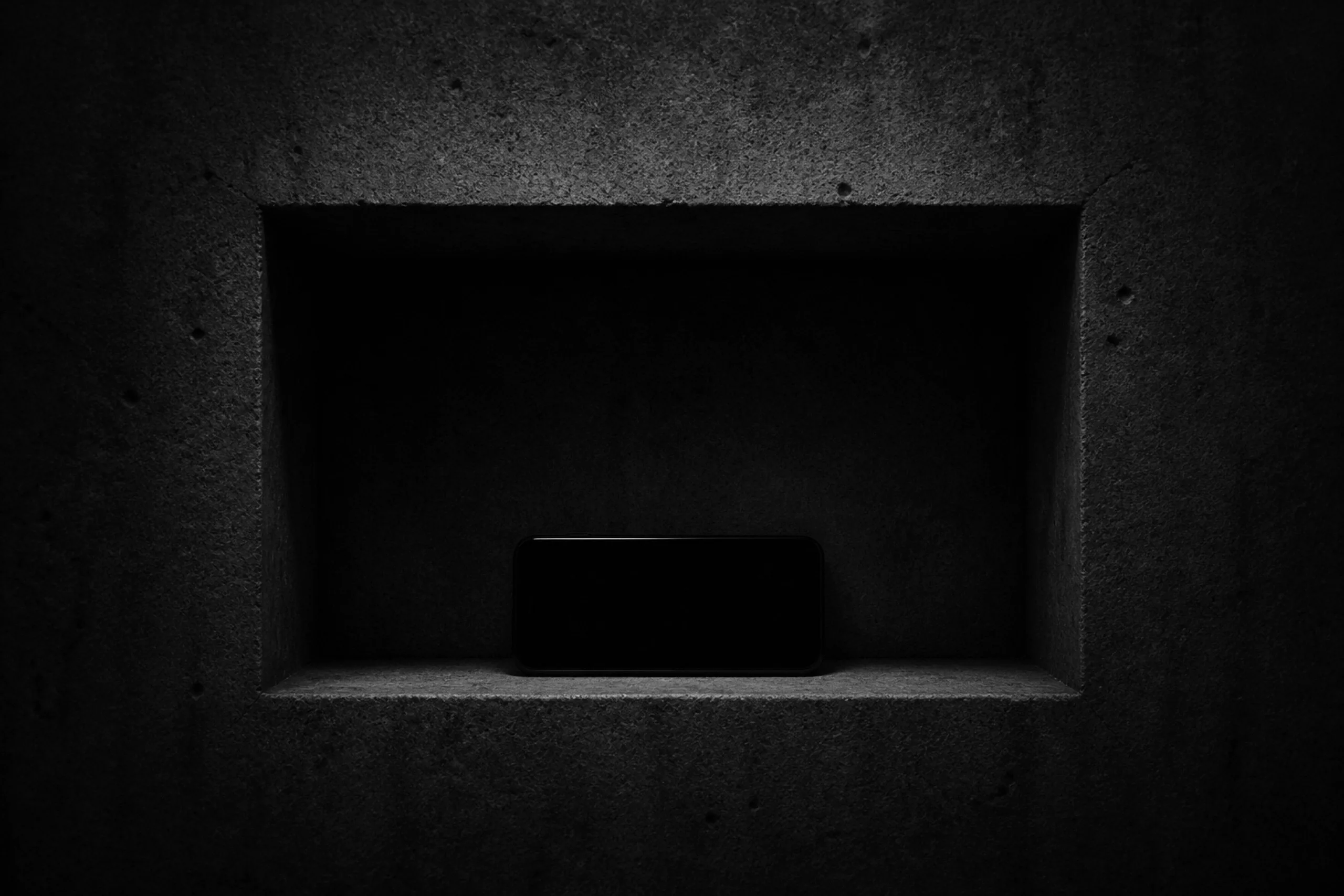 A phone resting inside a shadowed concrete niche